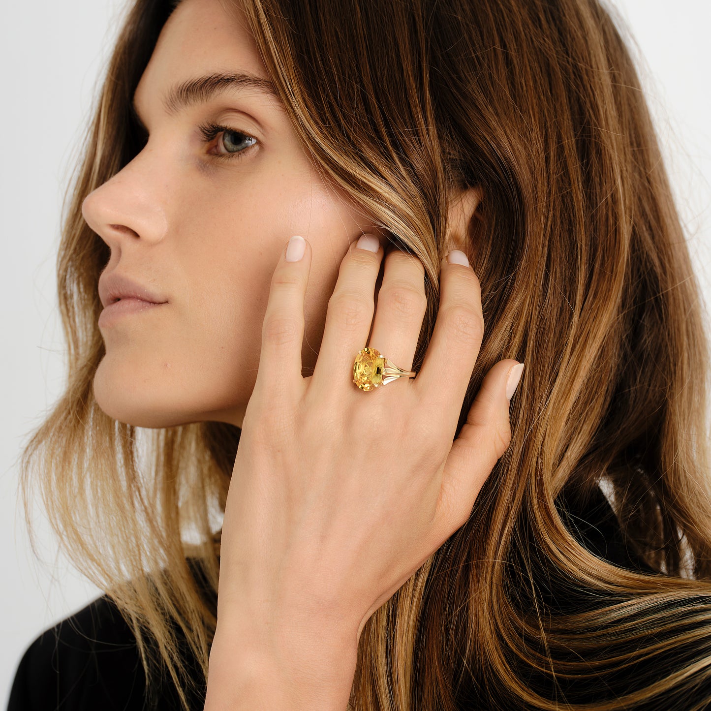 Woman wearing a gold ring with a yellow sapphire