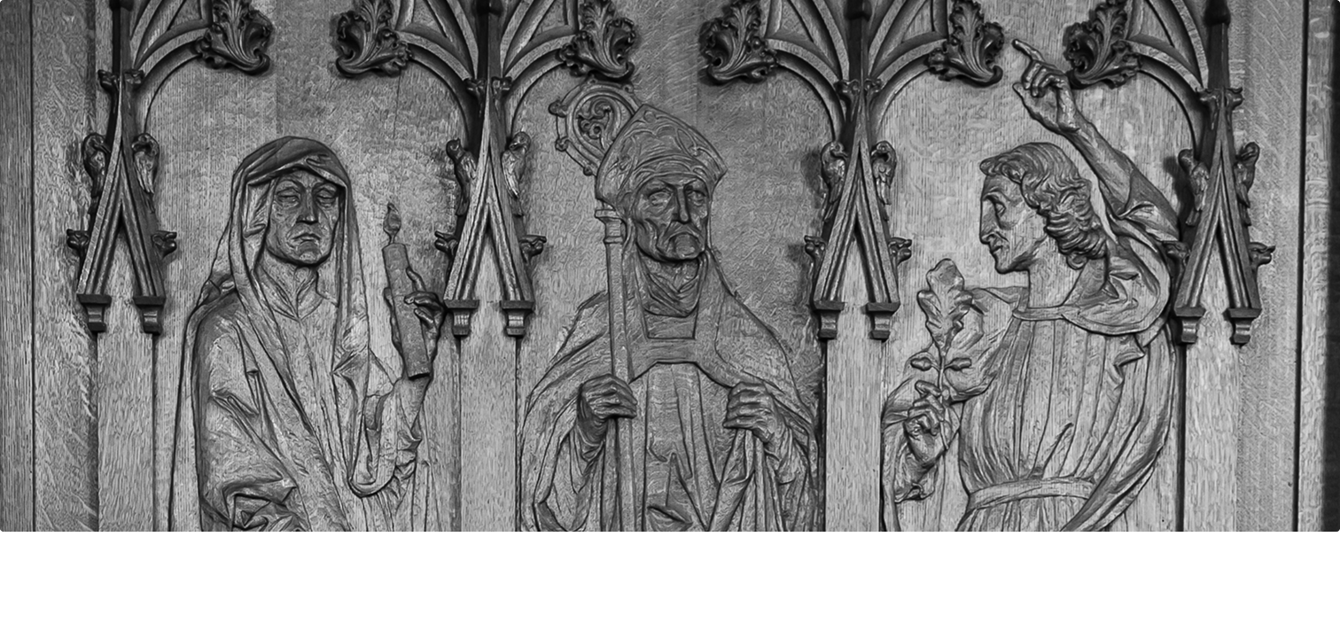 A carving showing three figures, the one in the center is a priest